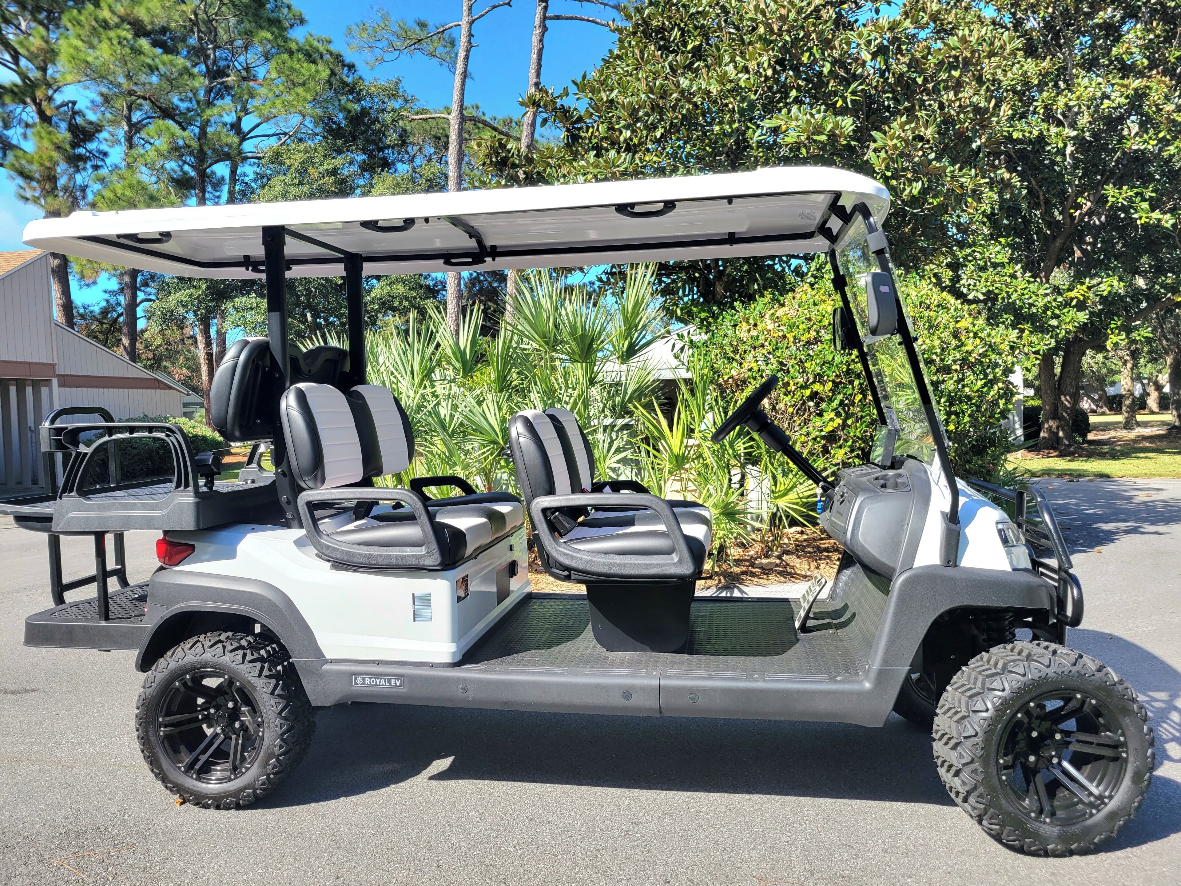 Un cart de golf amb una plataforma elevada, dos seients i un sostre.