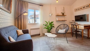 A modern living room with a sofa, a dining table, a TV, and a potted plant. - Home Chic Home Les Toits de l'Argenterie (Montpellier)