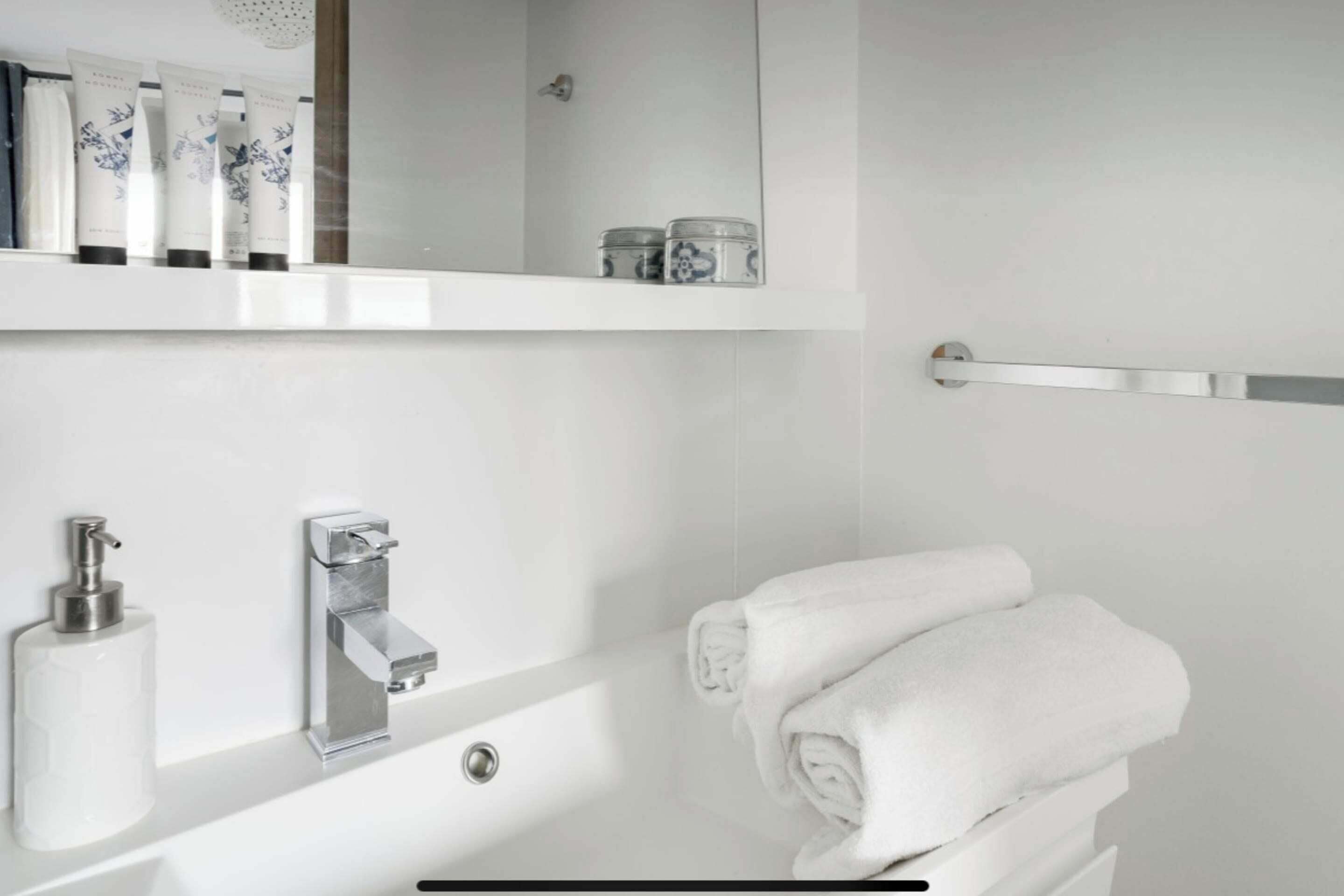 Une salle de bain moderne avec un lavabo blanc, un robinet chromé et un porte-serviettes.