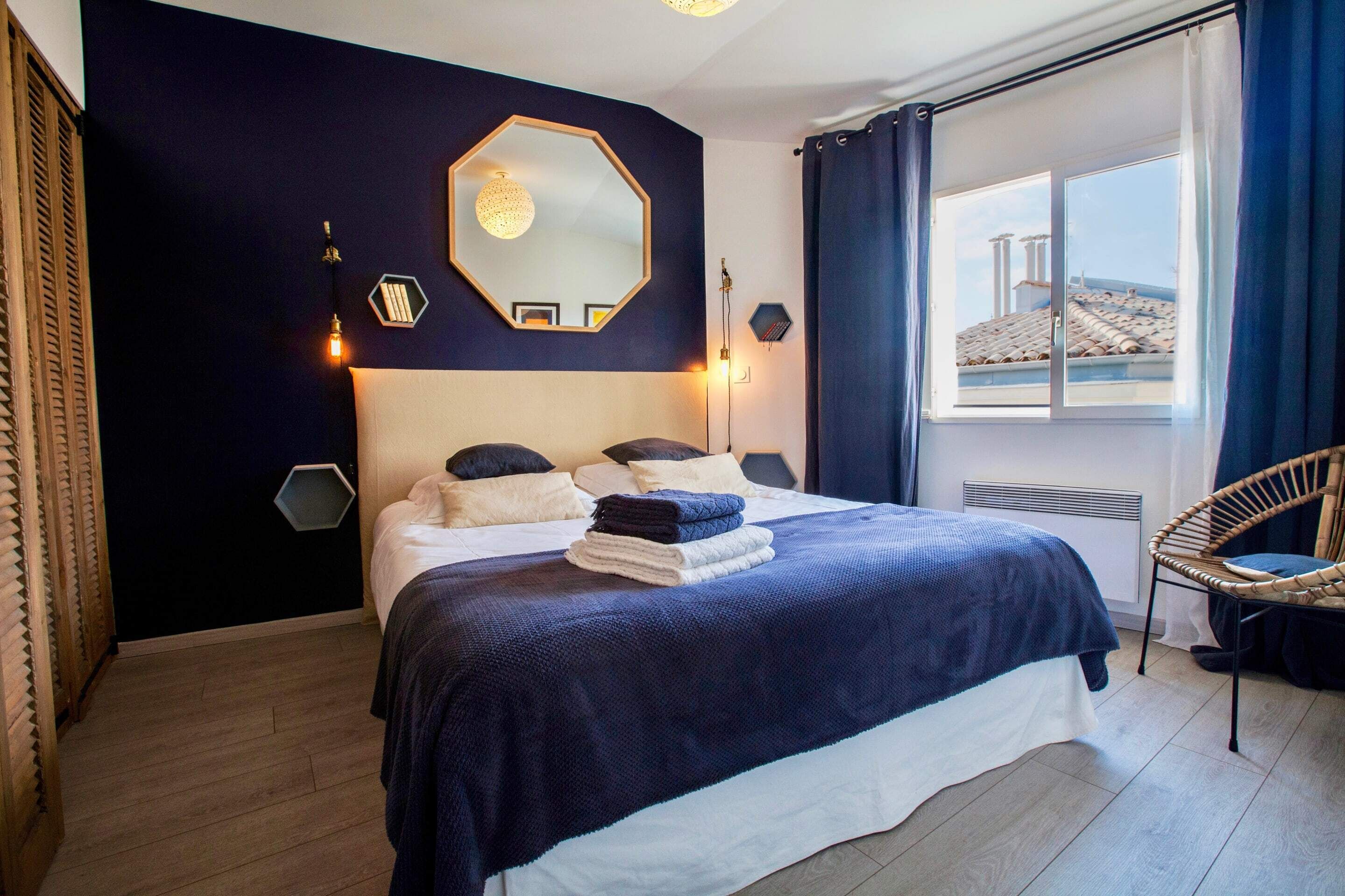 A modern hotel room with a large bed, a view of the cityscape, and a large mirror on the wall.