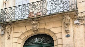 A historic building with a double green door, ornate metalwork above the door, and a plaque indicating it is the Hotel de Pomier. - Home Chic Home Les Toits de l'Argenterie (Montpellier)