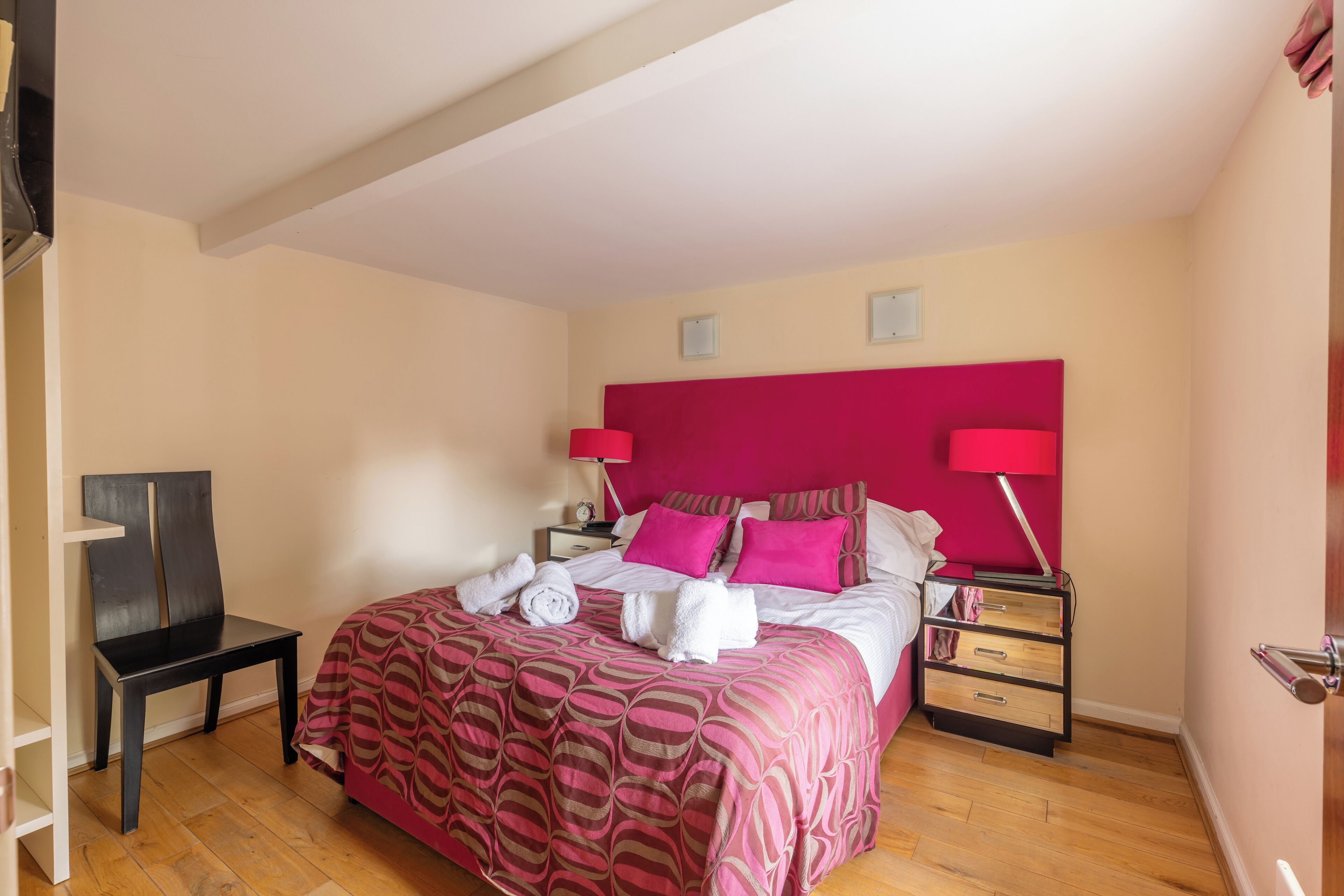 A bedroom with a bed, bedside tables, a chair, and a wardrobe.
