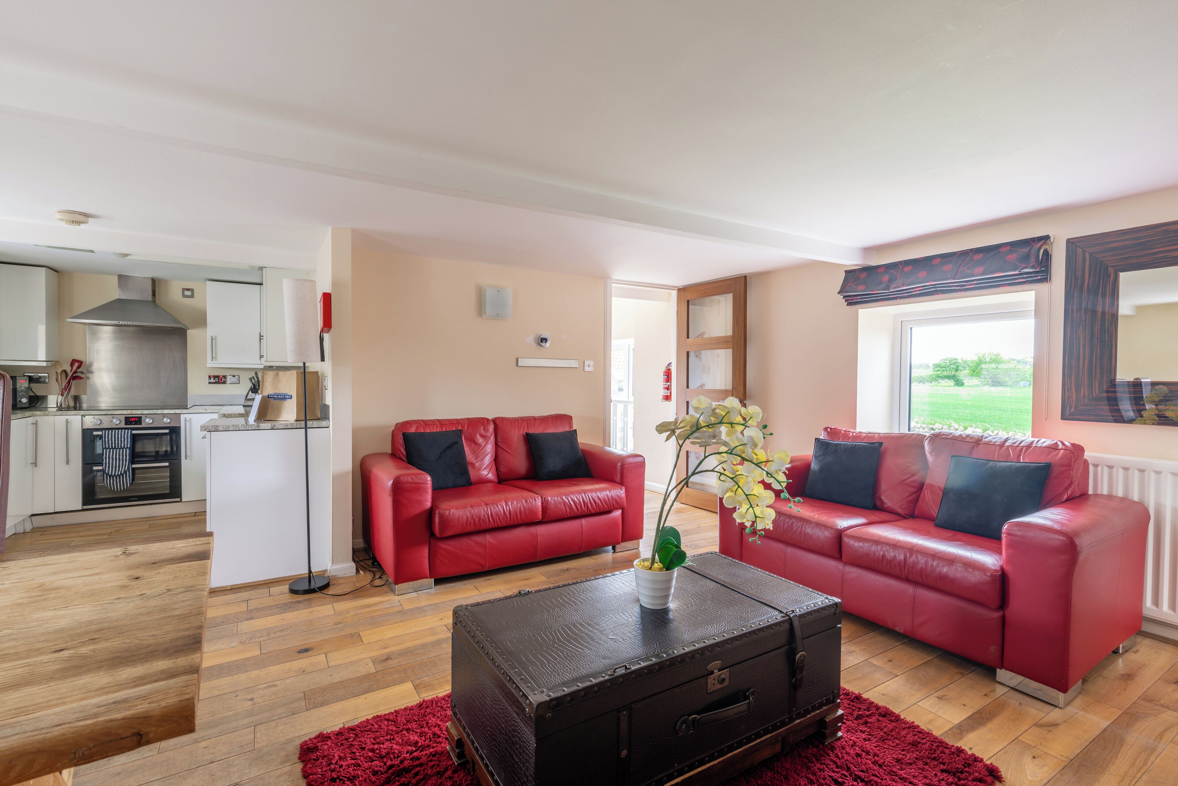 A living room with a red leather sofa, a black suitcase, and a red rug.