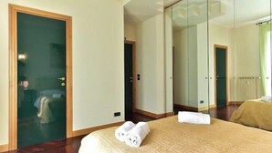 A hotel room with a bed, a mirror, and a door. - Elegant & Cozy Apartment in the heart of Rome (Roma)