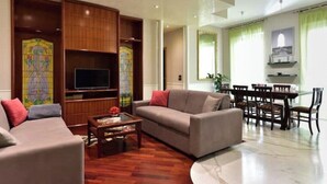 A living room with a sofa, coffee table, and TV, wooden paneling, and a dining area with chairs and a table. - Elegant & Cozy Apartment in the heart of Rome (Roma)