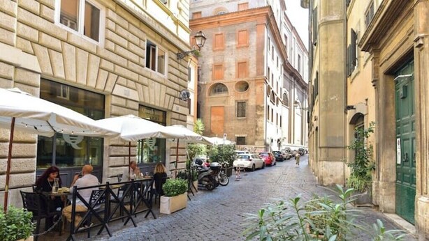 A cobblestone street with outdoor seating at a café, surrounded by historic buildings. - Elegant & Cozy Apartment in the heart of Rome (Roma)