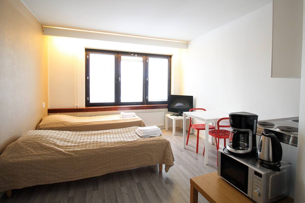 Una habitación con dos camas, televisión, cafetera y microondas.