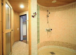 A wooden interior hallway leading to a bathroom with a shower area, tiled walls, and a visible drain. - Forenom Apartments Rauhankatu 16 (Lahti)