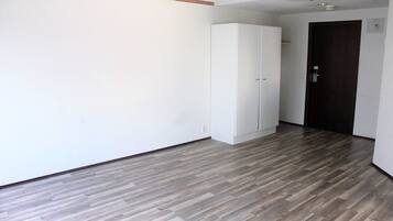 Una habitación con piso de madera, paredes blancas y un armario.