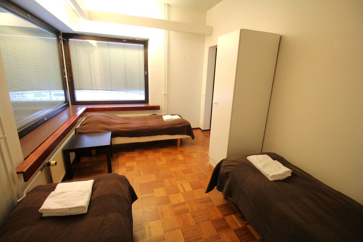 Una habitación con dos camas, una ventana con persianas, un radiador y un armario.