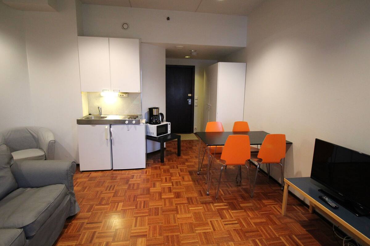 Un espacio habitable compacto con kitchenette, comedor y asientos.