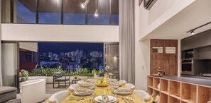 A dining area with a city view, a kitchen with modern appliances, and a balcony with plants. - Spacious & private apt w BBQ - Morph 1302 (Medellín)