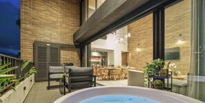A modern outdoor patio with a hot tub, seating area, and a dining space.