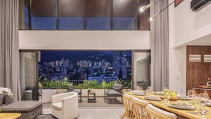 Un comedor moderno con vistas a la ciudad, un sofá y una mesa lista para comer.