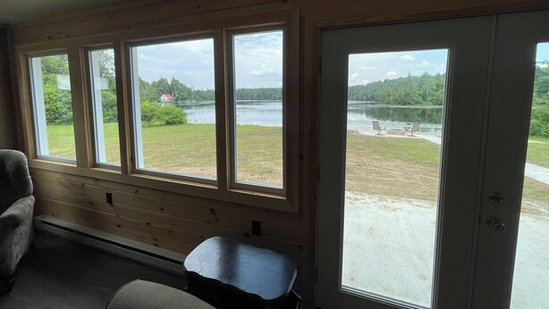 A room with large windows overlooking a lake and a grassy area.