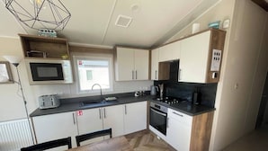 A modern kitchen with a microwave, toaster, sink, stove, and cabinets. - 3-bed Caravan - Haven Lakeland Leisure Park (Grange-over-Sands)
