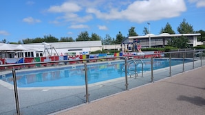 A swimming pool with a metal safety railing, surrounded by a paved walkway. - 3-bed Caravan - Haven Lakeland Leisure Park (Grange-over-Sands)