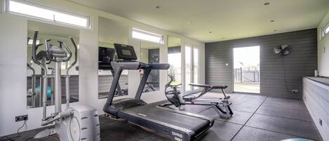 A gym with treadmills, elliptical machines, and exercise balls.