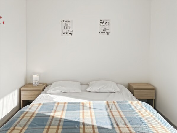 Un dormitorio con cama, dos mesitas de noche y dos cuadros en la pared.