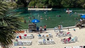 A beach with clear water, lounge chairs, and umbrellas.