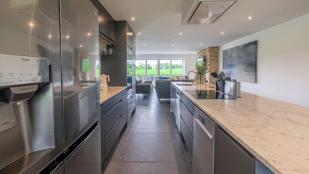 A modern kitchen with stainless steel appliances, a marble countertop, and a view of the outdoors. - The Duchess - North East Escapes (Bamburgh)