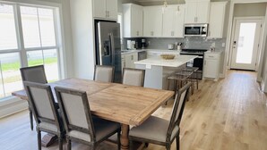 A modern kitchen with white cabinets, a central island, and a dining area with wooden chairs.