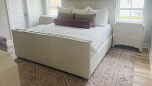 A bedroom with a large bed, two bedside tables, a window, and a door.