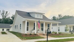 A single-story house with a front porch, a flag, and a mailbox.