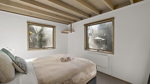 Cozy retreat with a single bed, two windows, and wooden beams.