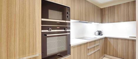 A modern kitchen with wooden cabinetry, a built-in oven, and a stainless steel range hood.