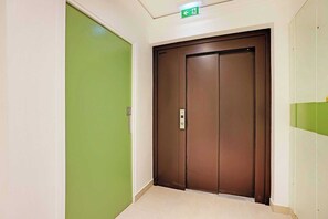A hallway with a green door and a brown elevator.