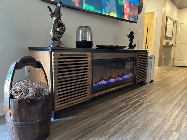Un salon moderne avec un meuble de rangement en bois, un téléviseur à écran plat et un aquarium.