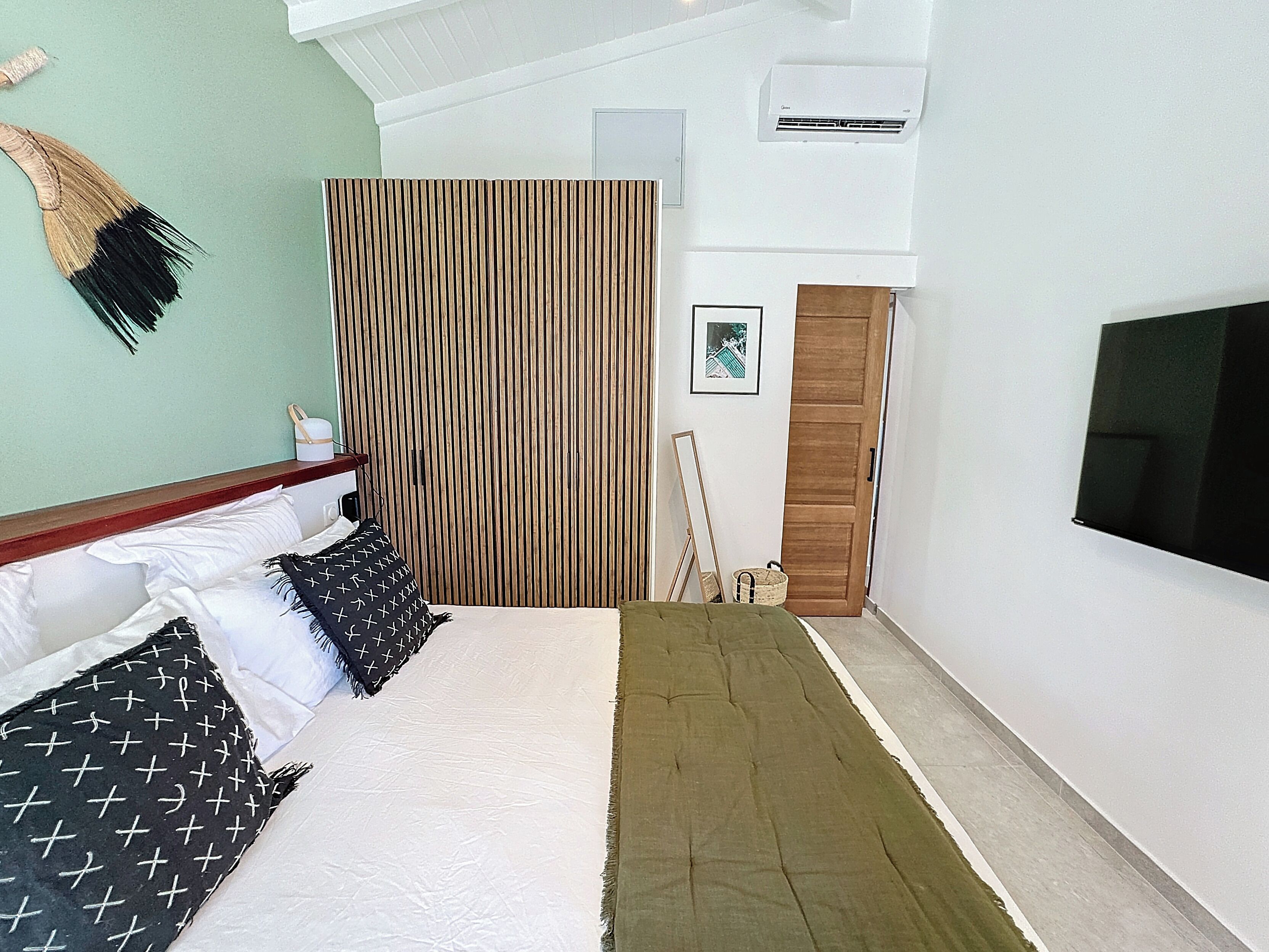 Une chambre à coucher avec un lit, une télévision, une armoire en bois et un rideau à rayures.
