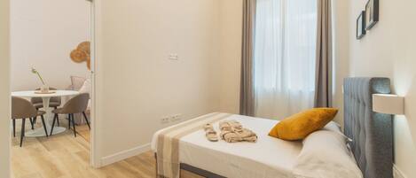 A modern hotel room with a bed, a desk, and a chair.