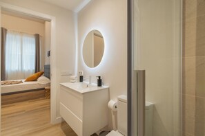 A modern bathroom with a round mirror, white sink, and toilet. - Urania Cádiz Apartments by Soho Boutique (Cádiz)