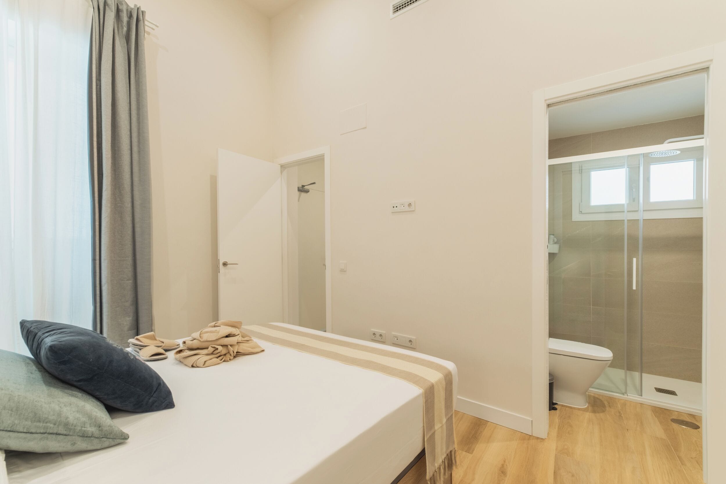 A bedroom with a bed, a bathroom with a shower, and a toilet.