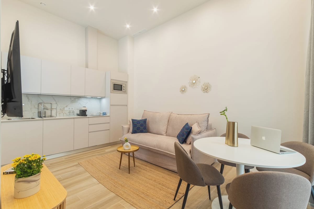 Un salon moderne avec un canapé, une table basse et un coin repas équipé d’un ordinateur portable et agrémenté d’un vase.