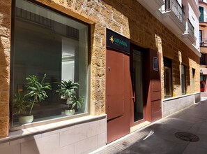 Ένα κτίριο με πρόσοψη από πέτρα, ένα μεγάλο παράθυρο με γλάστρες και φυτά, και μια επιγραφή που αναγράφει «URANIA HOTELS».
