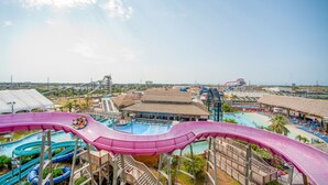 A water park with multiple slides and pools, including a large pink slide, and a beach area with umbrellas and lounge chairs. - SPEND YOUR SPRING BREAK IN A HOT TUB/HEATED POOL on the ISLAND! (Galveston)
