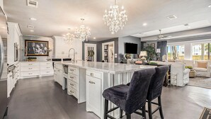 A spacious kitchen with a large island, white cabinetry, and a chandelier. - SPEND YOUR SPRING BREAK IN A HOT TUB/HEATED POOL on the ISLAND! (Galveston)