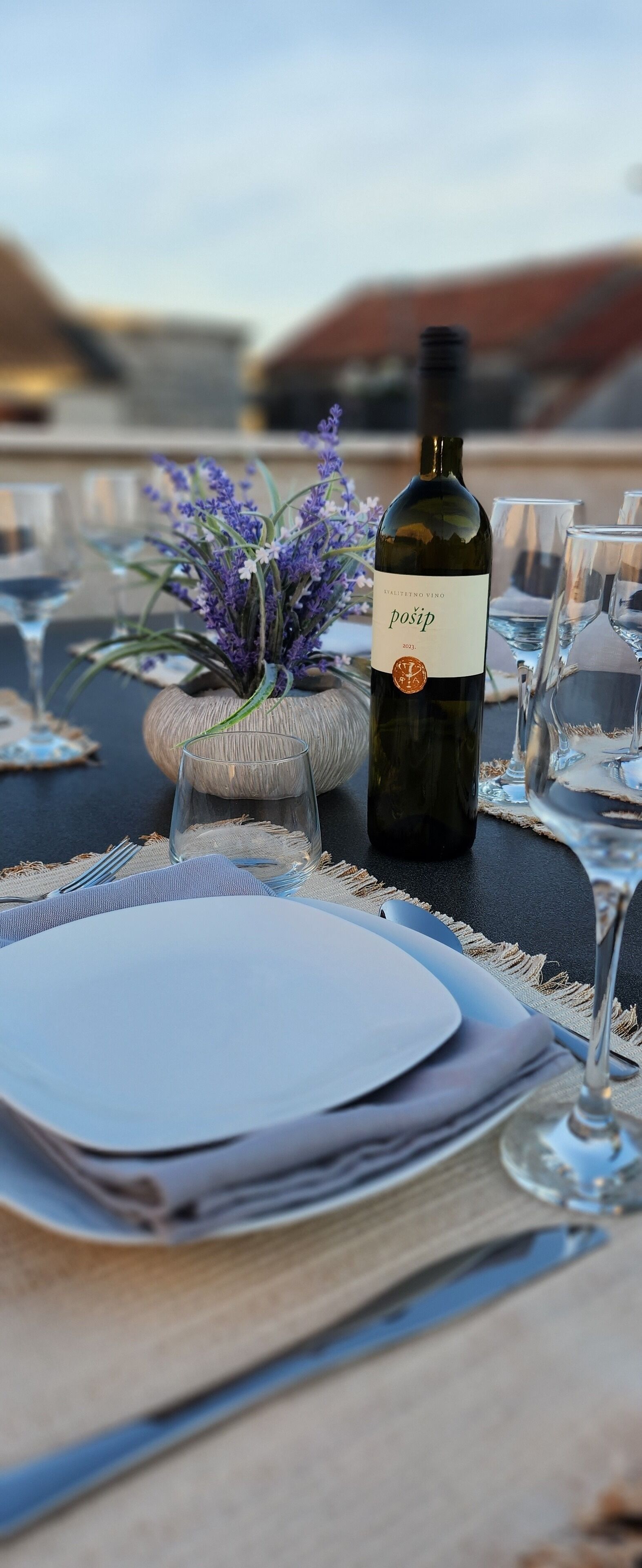 A table set for dining with a bottle of wine, glasses, and a vase with flowers.