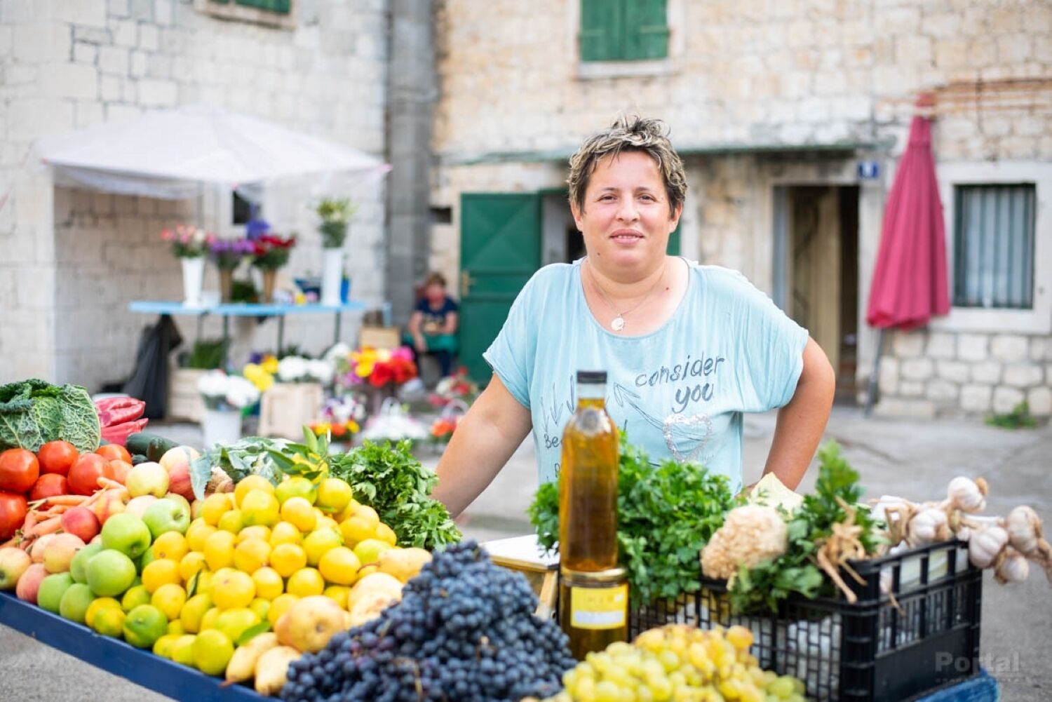 Ένα πάγκος στην αγορά με φρέσκα προϊόντα, όπως μήλα, λεμόνια και σκόρδο.
