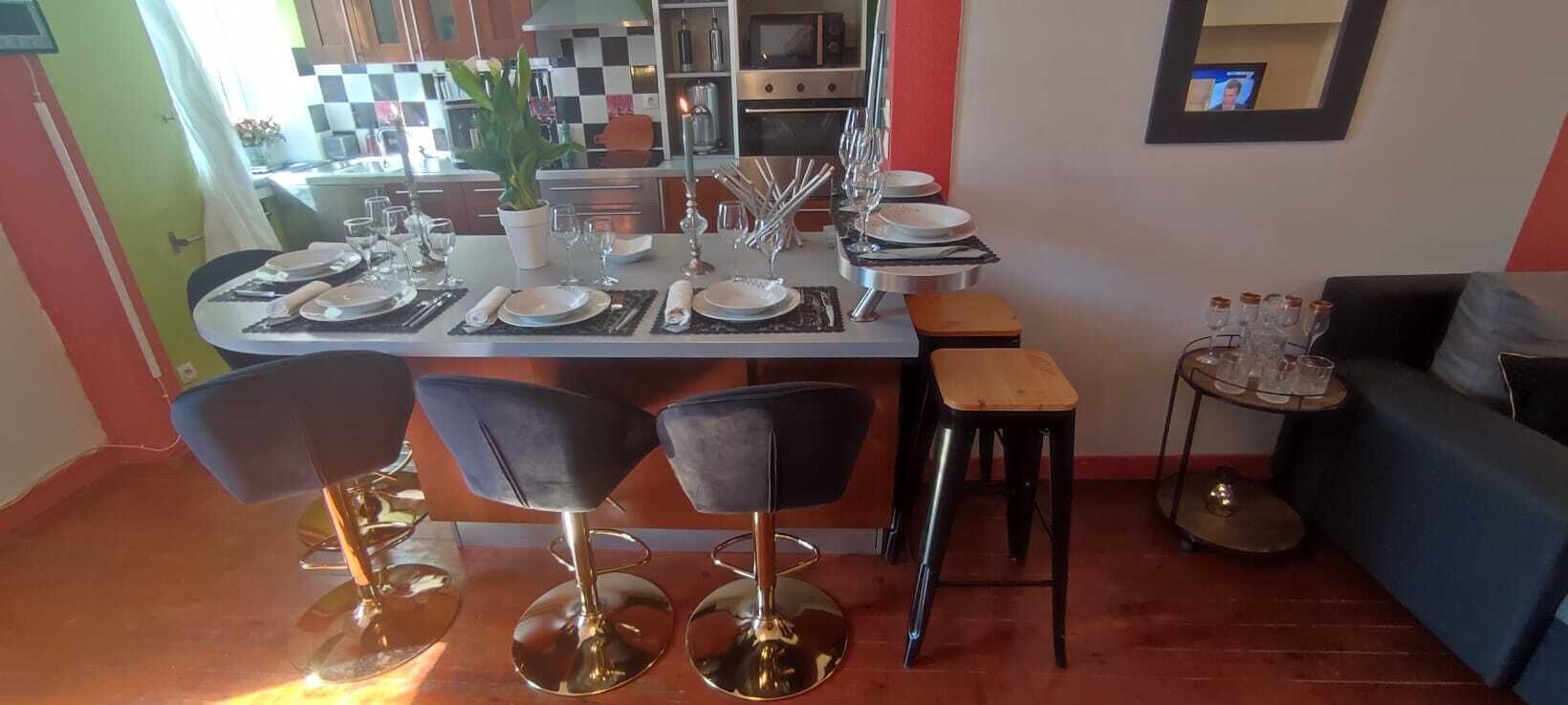 Eine moderne Küche mit Essbereich, inklusive Barhocker, einem kleinen Tisch und einer Couch.