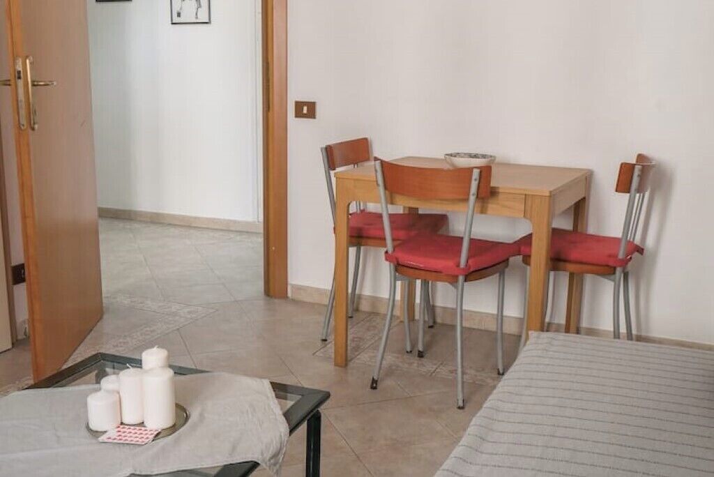 A room with a bed, a table with chairs, and a door leading to another room.