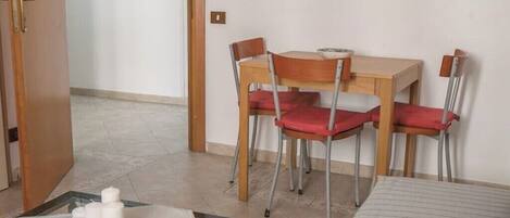 A room with a bed, a table with chairs, and a door leading to another room.