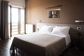 Relax in a serene space with a large bed, wall-mounted lamp, and a potted plant.