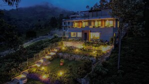 A modern two-story building with a well-lit garden and a staircase leading to the entrance. - Sri Vidhya Residency (Kotagiri)