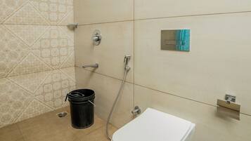 Un baño con inodoro, ducha y perchero para toallas.