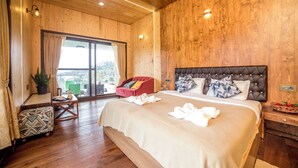 A wooden-paneled bedroom with a large bed, a red chair, a small table, and a view through a glass door. - Sri Vidhya Residency (Kotagiri)