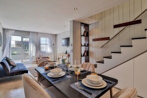 Cozy living space with a dining table for four, comfortable sofa, and a contemporary staircase.